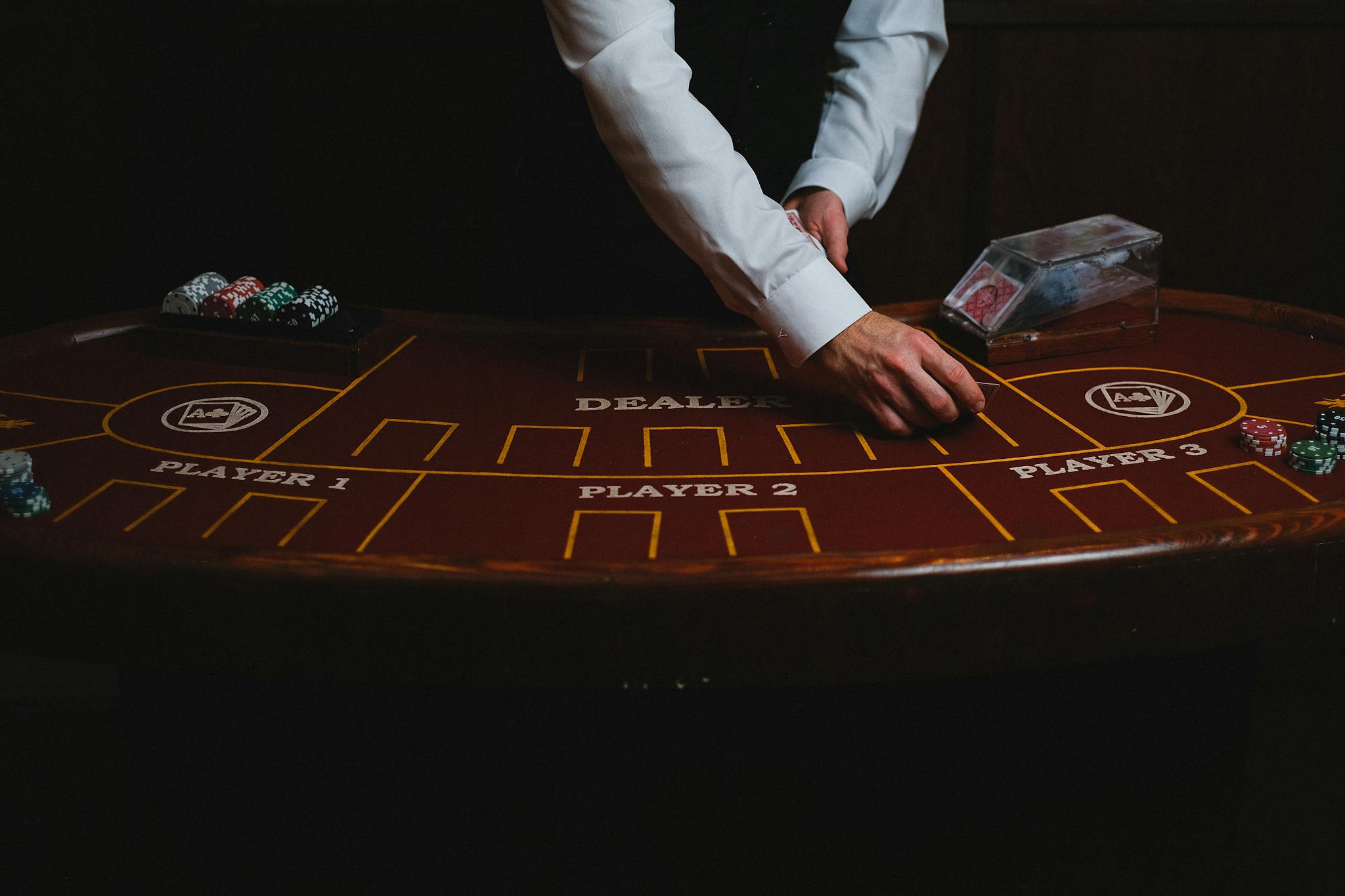 A croupier deals cards on a dimly lit casino table, showcasing gambling atmosphere.